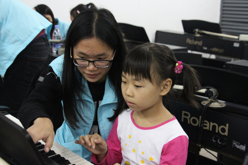 “小老师”耐心辅导小孩弹琴-800